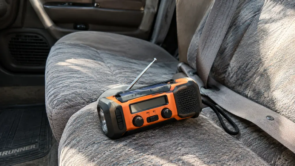 A handheld weather radio on the passenger seat of an older Toyota 4Runner with a seatbelt holding it in place